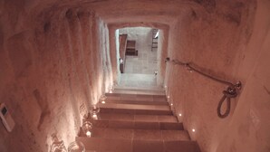 A stone staircase leading to a higher level, with a handrail on the right and a door at the top.