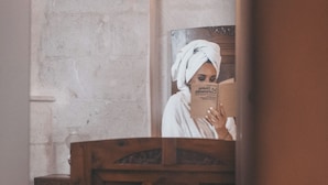 A bathroom with a wooden vanity, a mirror, and a towel hanging on the wall.