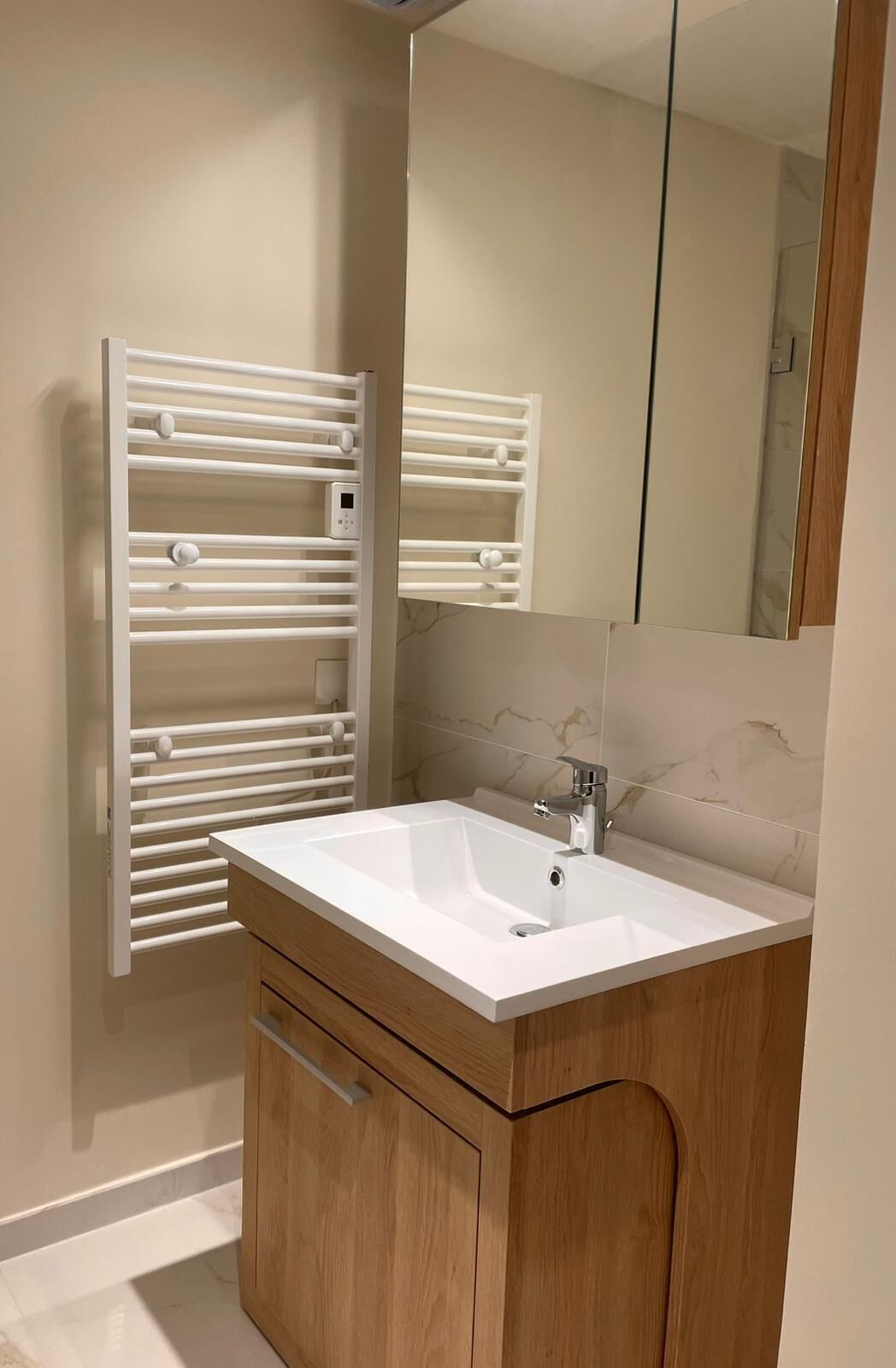 Ein Badezimmer mit einem weißen Waschbecken, einem Holzkabinet und einem Handtuchhalter.
