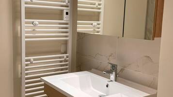 Ein Badezimmer mit einem weißen Waschbecken, einem Holzkabinet und einem Handtuchhalter.