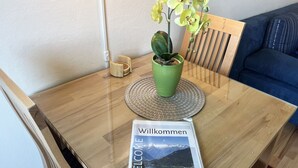 Una mesa de madera con una planta en maceta verde, un letrero de bienvenida y una silla de madera.