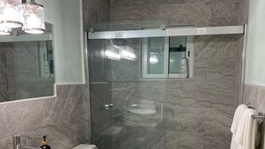 A modern bathroom with a glass-enclosed shower, a white sink, and a toilet.