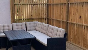 A wooden deck with a dark wicker sofa and a matching table.