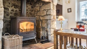 Una chimenea de piedra con un estufa de leña moderna, una cesta de mimbre y una mesa con productos horneados.