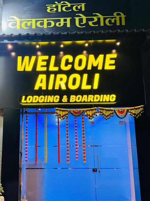 A hotel entrance with a neon sign reading "WELCOME AIROLI" and "LODGING & BOARDING". - Welcome Airoli (Navi Mumbai)