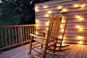 Een houten schommelstoel op een terras met een lichtslingering.