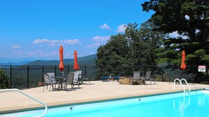 A swimming pool with a view of mountains, surrounded by lounge chairs and umbrellas.