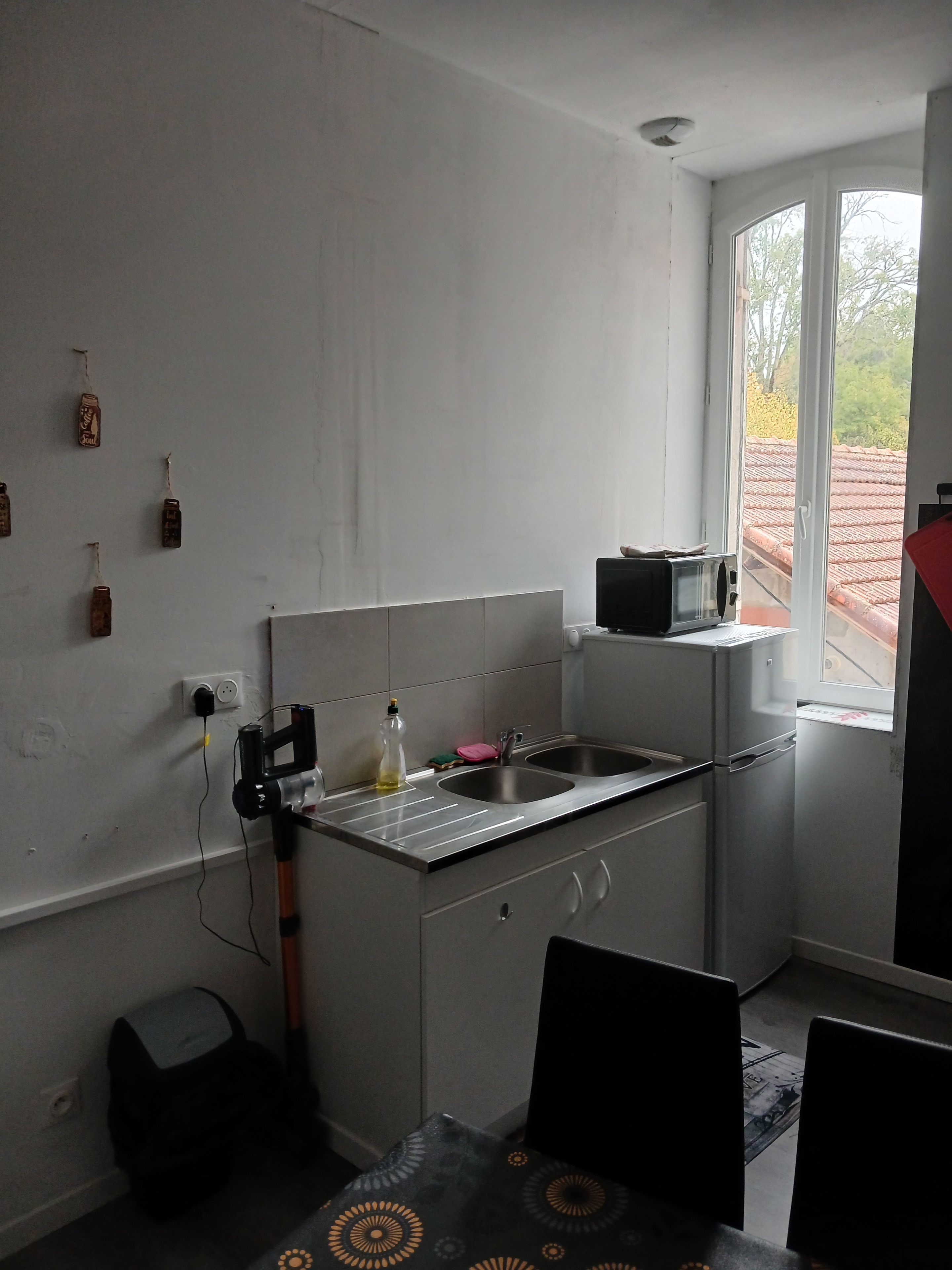A compact kitchen with a sink, a microwave, and a window providing a view of the outside.
