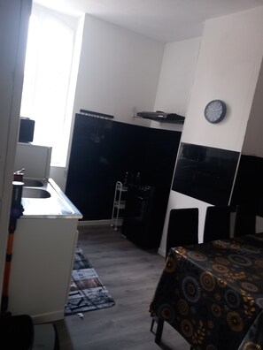 Een kleine keuken met een spoelbak, een magnetron en een klok aan de muur.