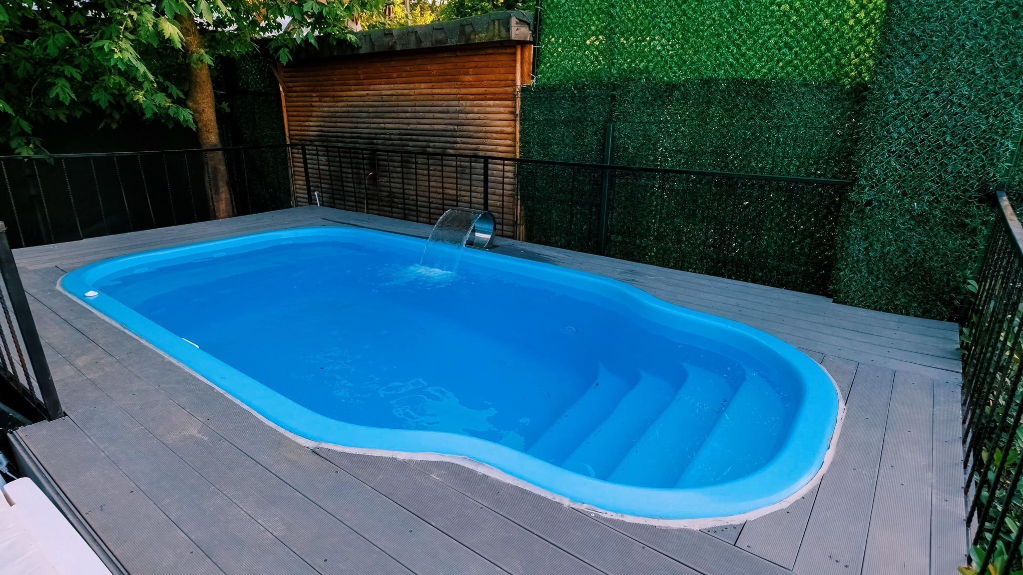 A rectangular swimming pool with a wooden deck surrounding it.