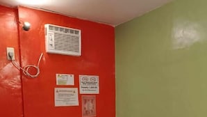 Ett litet rum med en röd vägg, en grön vägg, ett vitt bord och två röda stolar. Det finns skyltar på väggen, bland annat en skylt som förbjuder rökning.