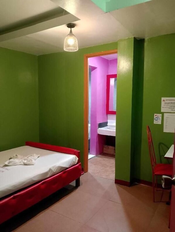 A room with a single bed, a chair, and a small table. - WJV INN PALAWAN (Liloan)