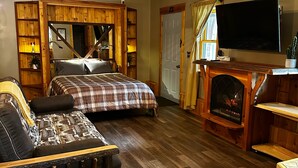 A cozy room with a bed, a bench, a fireplace, and a television.