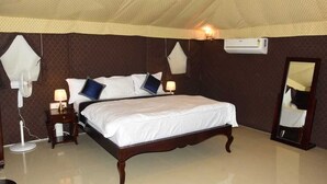 A bedroom with a large bed, a bedside table with a lamp, a wall-mounted air conditioner, and a mirror. - Riyasat Panthera (Bali)