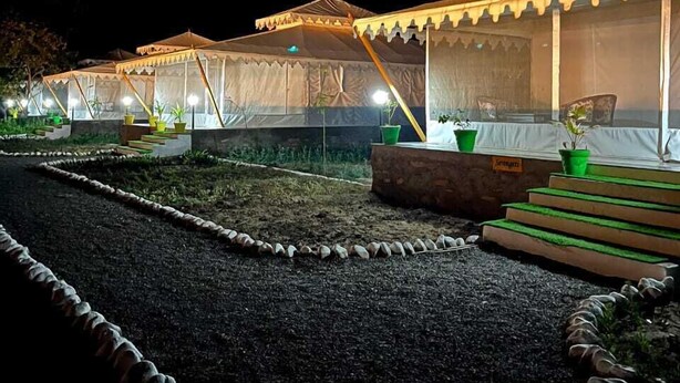 A series of tents with a covered walkway and steps leading to a covered seating area. - Riyasat Panthera (Bali)