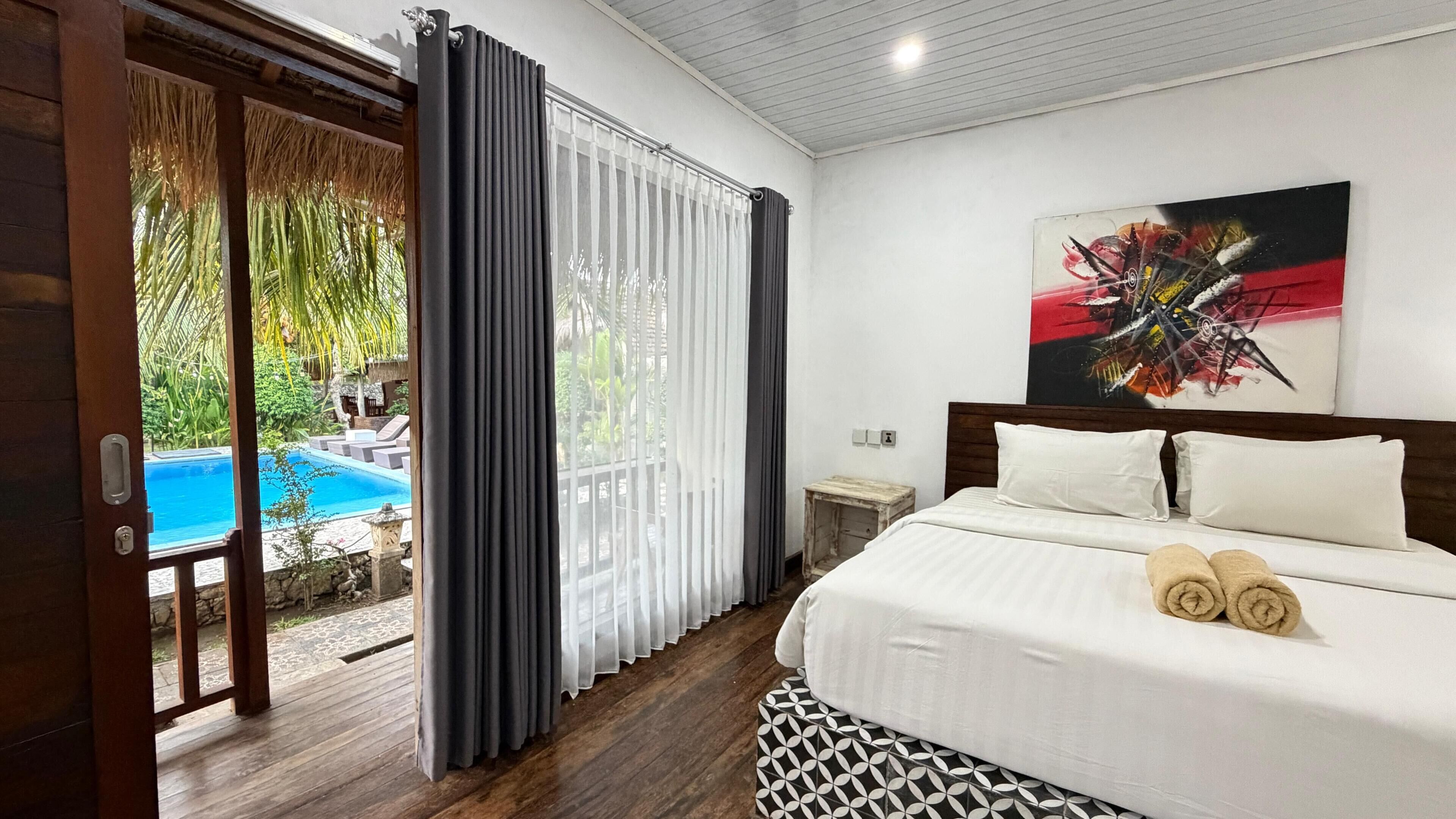 Ein Hotelzimmer mit Bett, einem Bild, Blick auf einen Swimmingpool und Holzboden.