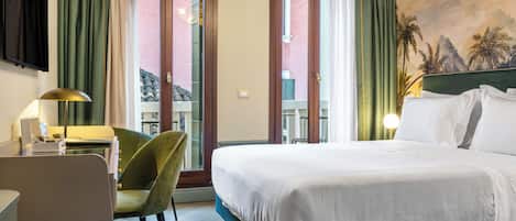 Habitación de hotel con cama, escritorio, silla y vistas al exterior.