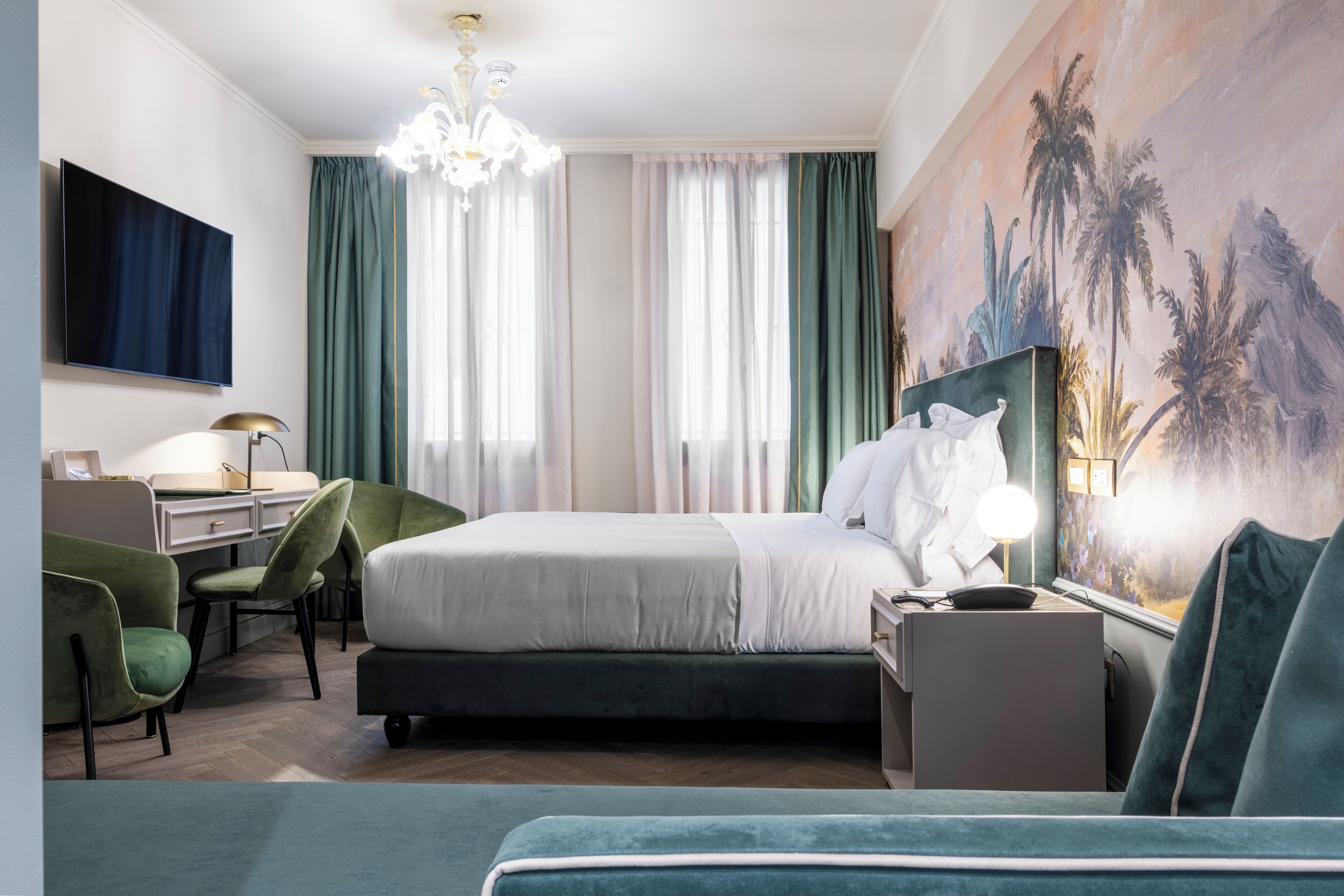 Una habitación de hotel con cama, escritorio, silla y un cuadro grande en la pared.