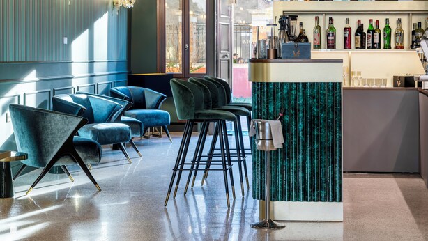 Una zona de bar con diversas opciones de asientos, una barra y una variedad de botellas a la vista.