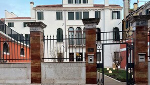 Una entrada cerrada con puerta a un edificio de estilo arquitectónico clásico, que presenta una placa numérica destacada y un área frontal empedrada y bien cuidada.