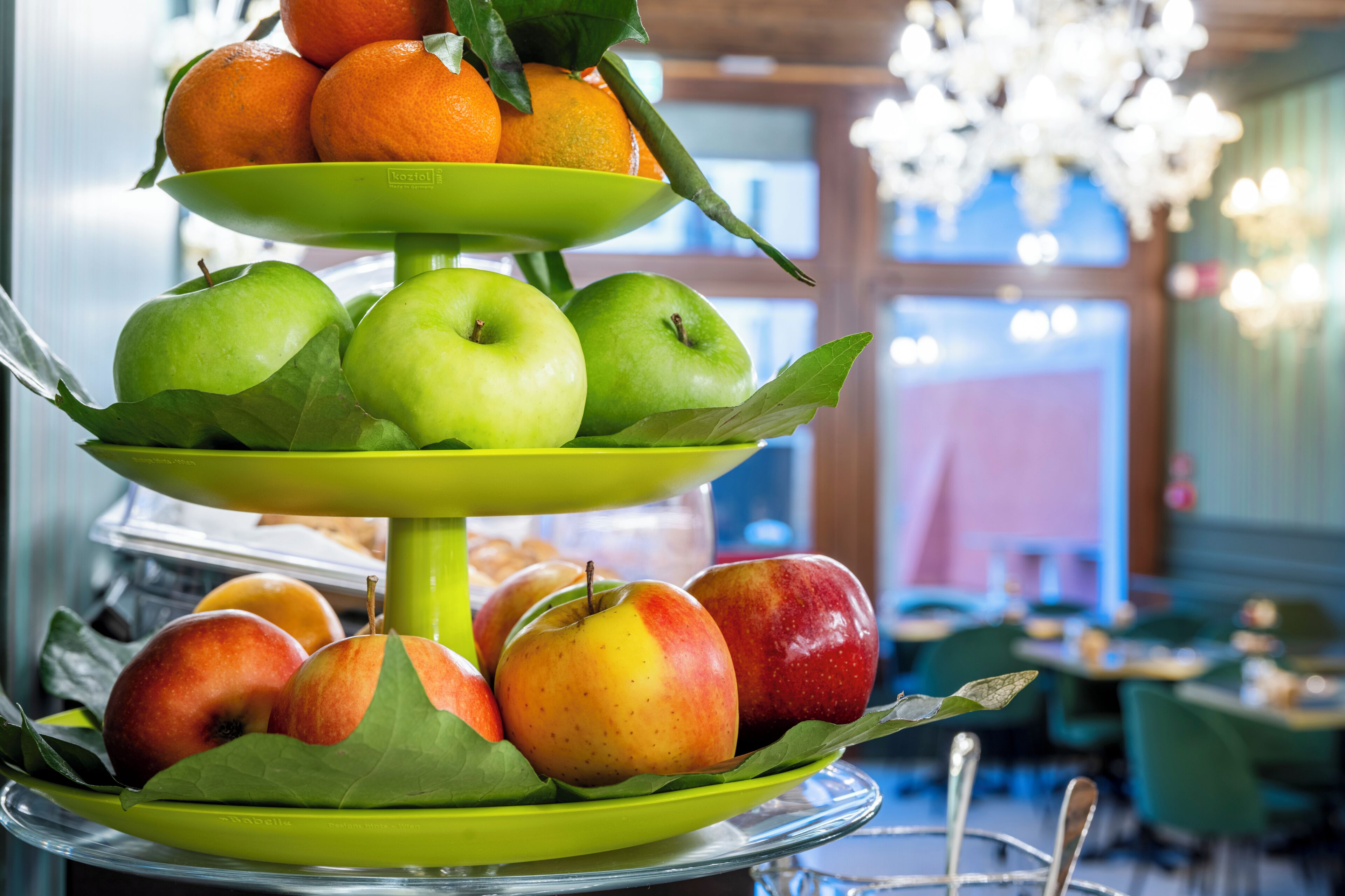 A multi-tiered fruit stand with apples and oranges.