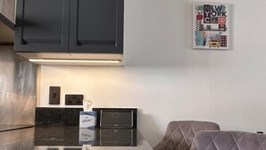 Uma cozinha com armários escuros, bancada, cafeteira e um cartaz fixado na parede.