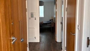 Um corredor com portas de madeira, um lustre no teto e uma cama ao fundo.