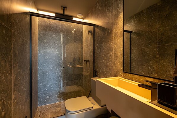 A modern bathroom with a glass-enclosed shower, a white toilet, and a large mirror above a bathtub.