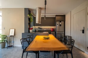 Een moderne keuken met een eettafel, stoelen en een hangende lamp.