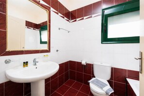 A bathroom with a white sink, a mirror, a toilet, and red-tiled walls. - Villa Iris - Three Bedroom Villa, Sleeps 6 (Kefalas)
