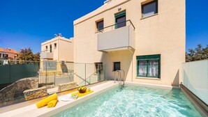 En modern byggnad med en swimmingpool, en stenmur och ett glasräcke.