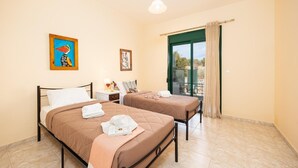 A hotel room with two beds, a balcony with a view, and artwork on the walls.