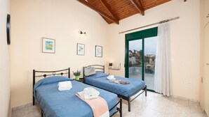 A bedroom with two beds, a balcony, and a view of the city. - Villa Yvonne - Three Bedroom Villa, Sleeps 6 (Kefalas)