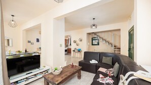 A living room with a flat-screen TV, wooden coffee table, and a sofa. There is a staircase leading to another level. - Villa Yvonne - Three Bedroom Villa, Sleeps 6 (Kefalas)
