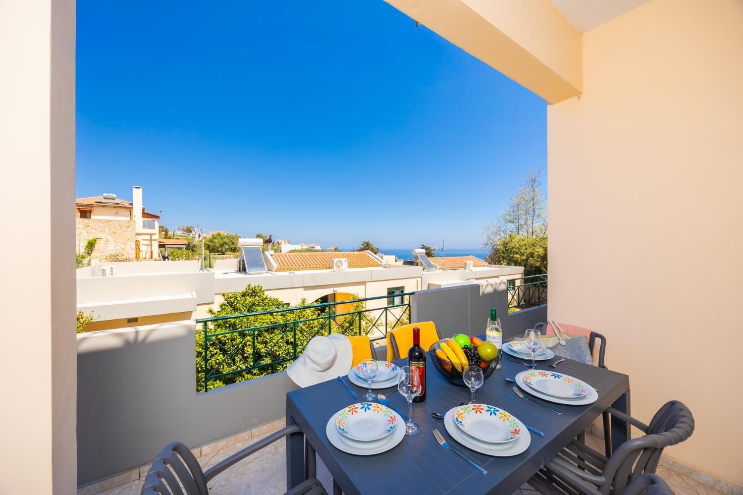 A balcony with a table set for dining, overlooking a coastal view.