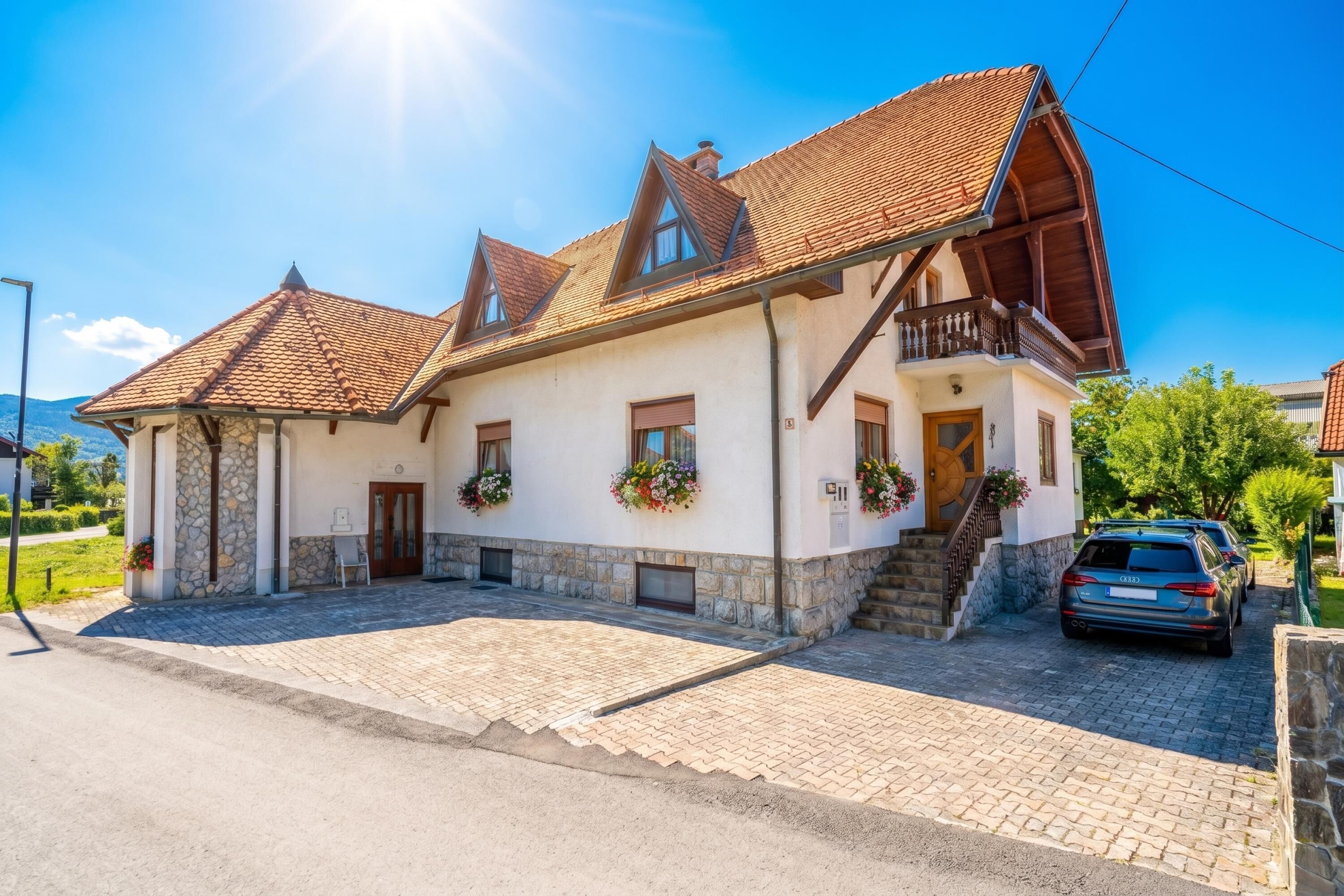 A two-story building with a stone facade, a tiled roof, and a balcony.
