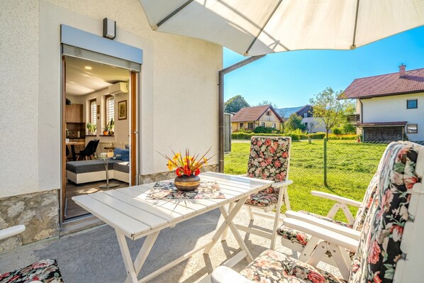 An outdoor patio with a table and chairs, a view of the neighborhood, and a house in the background.