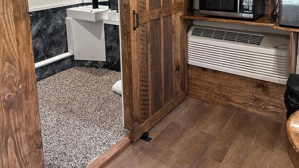 A kitchen with a sliding barn door, a microwave, a toaster, and a refrigerator. - Deluxe Cabin B at Elk Creek Escape (Hillsgrove)