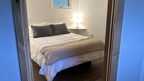 A bedroom with a bed, a nightstand, a window, and a ceiling light. - Deluxe Cabin B at Elk Creek Escape (Hillsgrove)