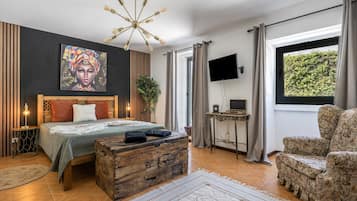 A modern bedroom with a bed, a television, a wooden chest, and a large window.