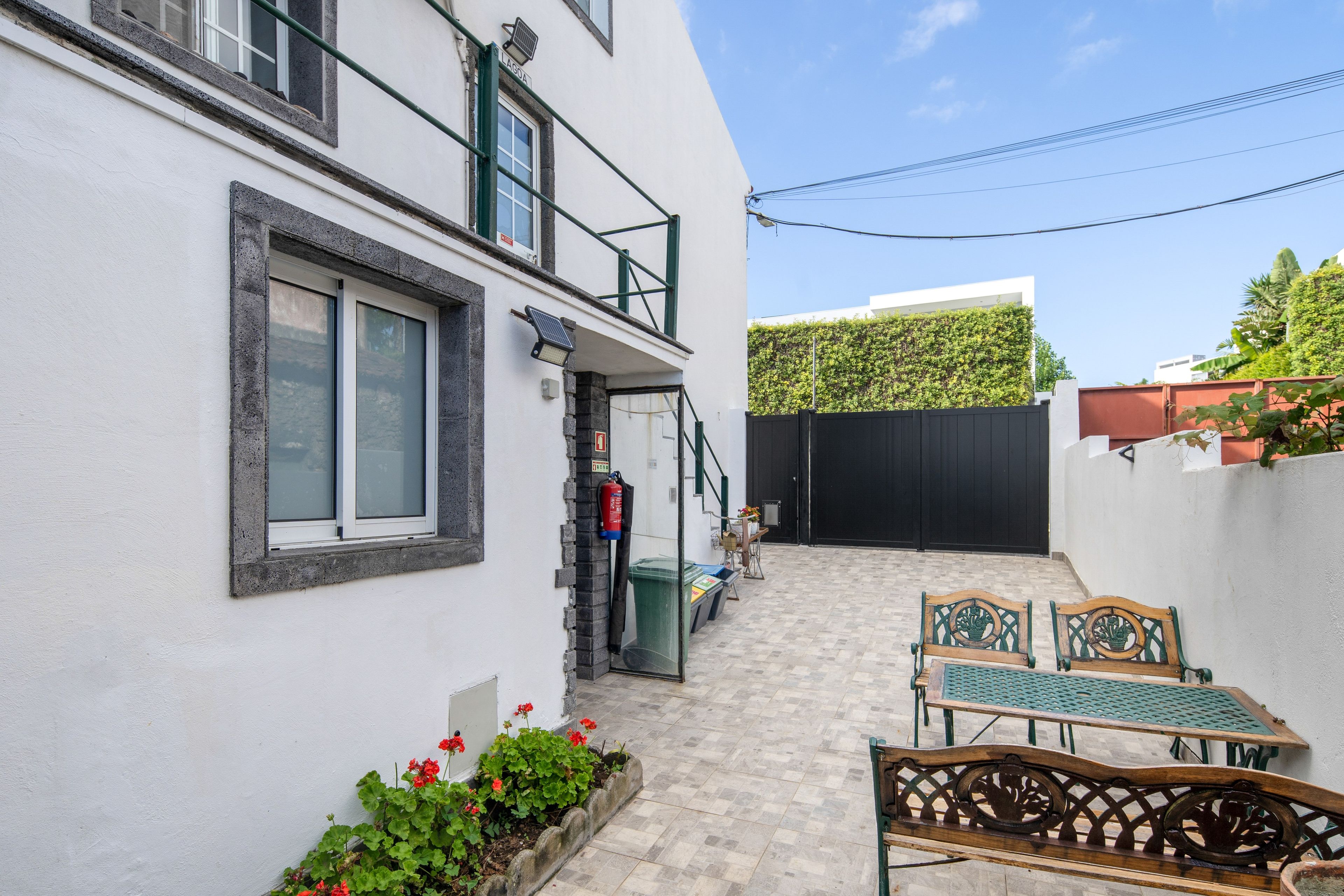 A courtyard with a covered seating area, a fire extinguisher, and a gated entrance.