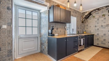 Una cocina moderna con horno empotrado, estufa y pileta. Hay una ventana con vista al exterior, y la cocina tiene un salpicadero de cerámica.