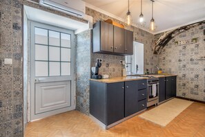 Cozinha moderna com forno embutido, fogão e pia. Há uma janela com vista para o exterior, e a cozinha tem painel de azulejos.