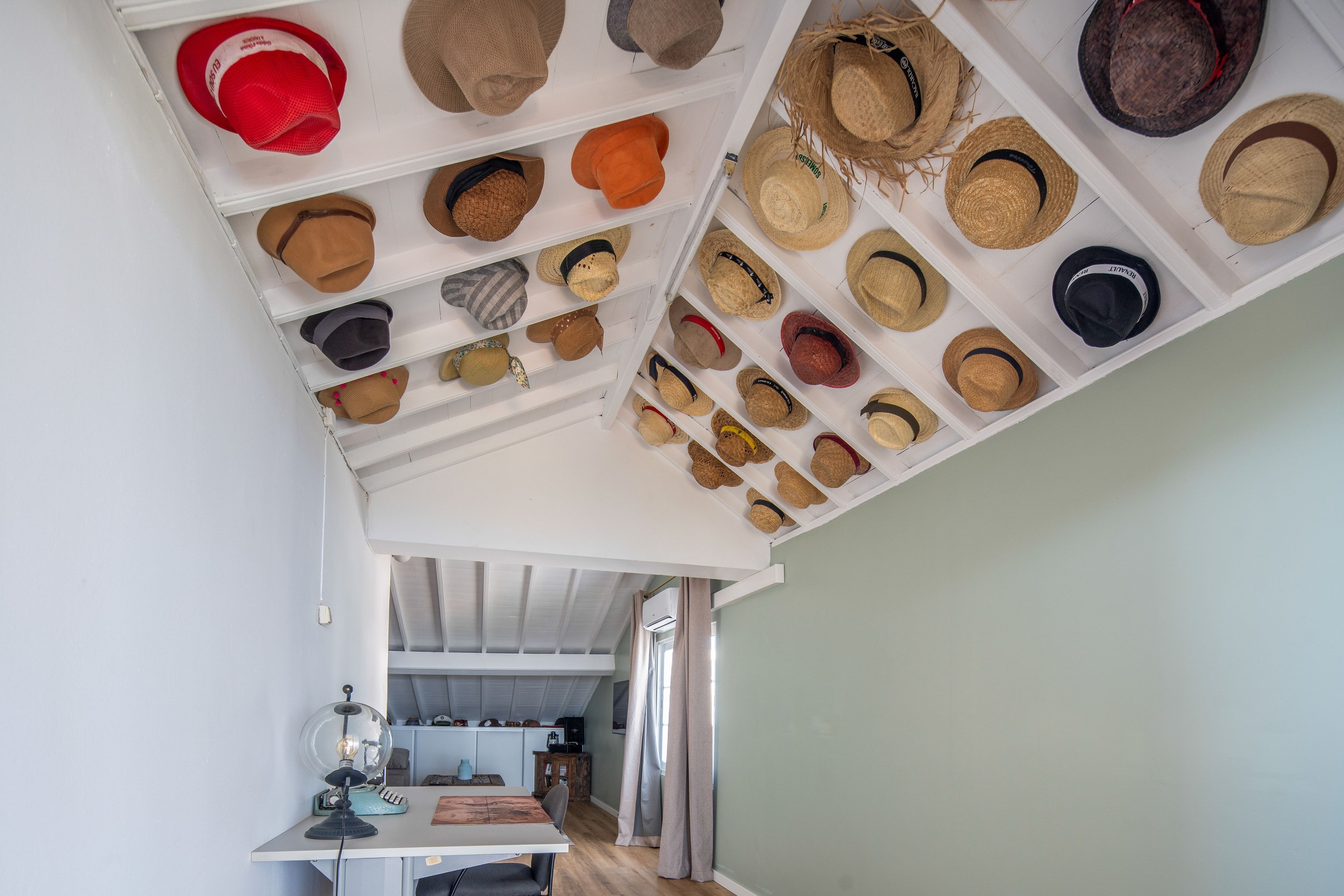 A room with a sloped ceiling displaying a collection of hats.