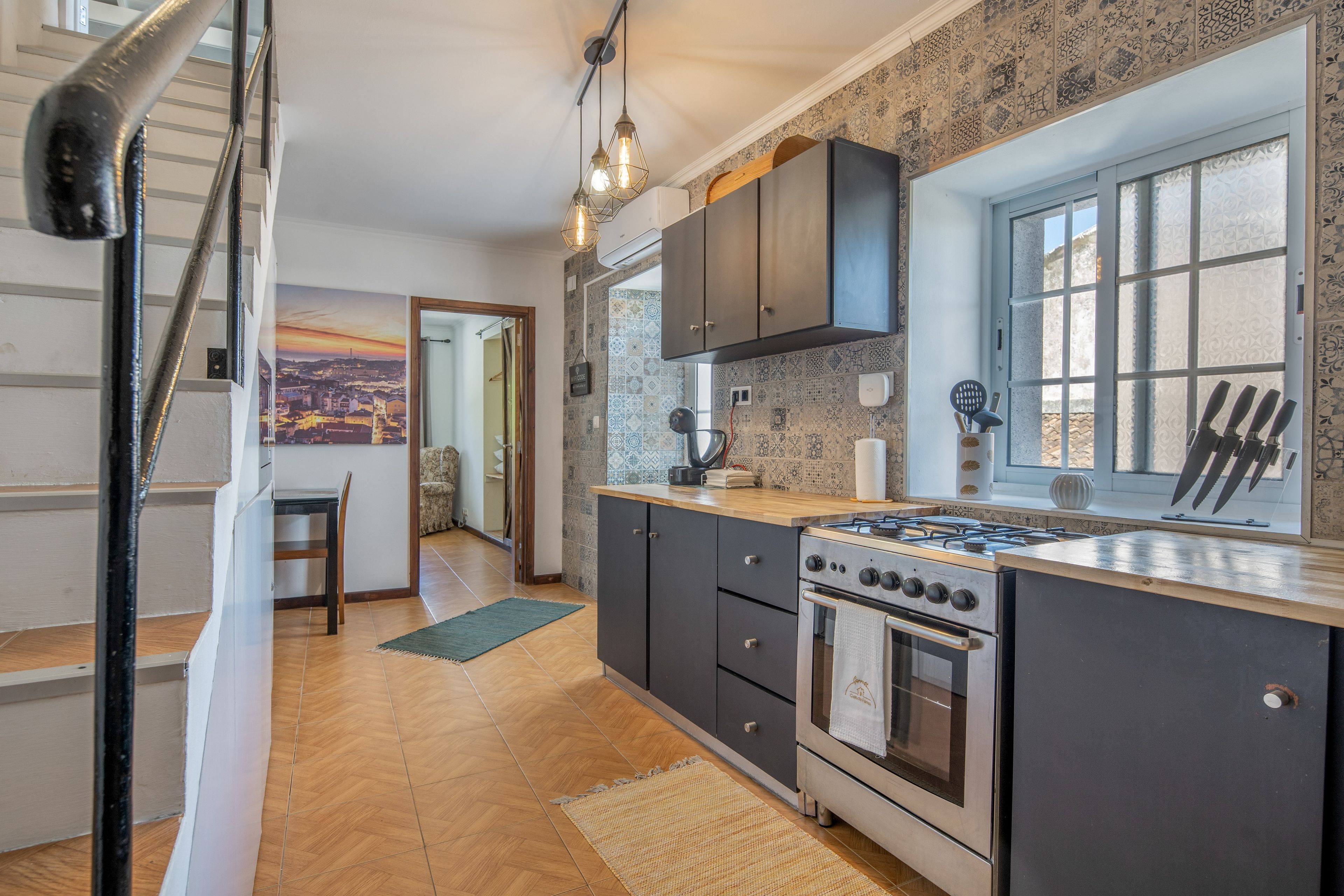A modern kitchen with a gas stove, dark cabinets, and a large window.