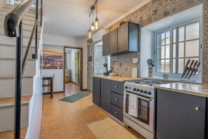 A modern kitchen with a gas stove, dark cabinets, and a large window.