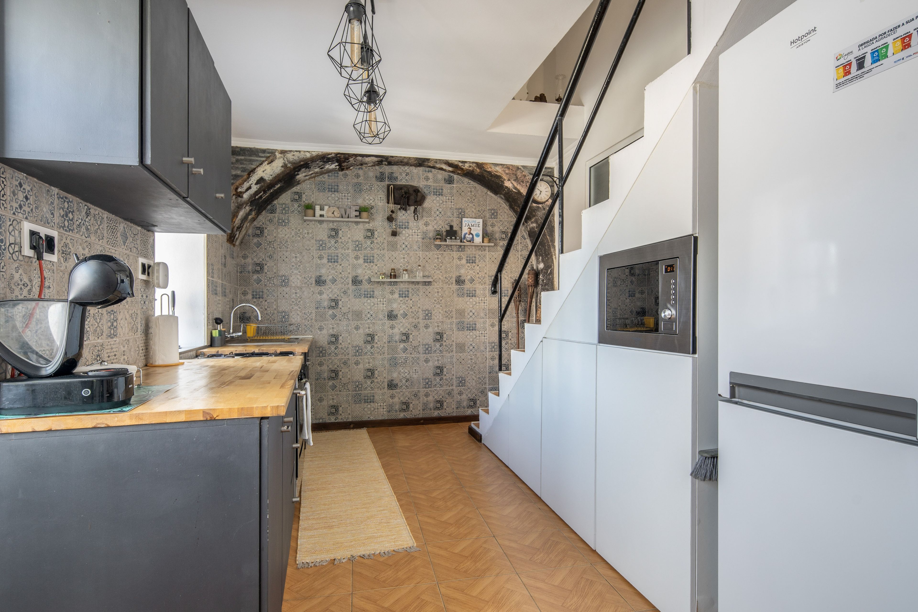 A kitchen with a wooden countertop, a built-in oven, and a white refrigerator.
