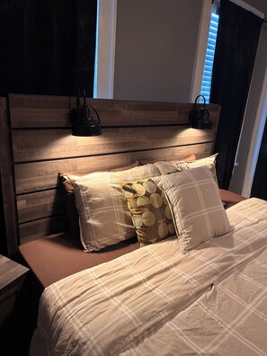 A bed with a wooden headboard, two pillows, and a bedside lamp.
