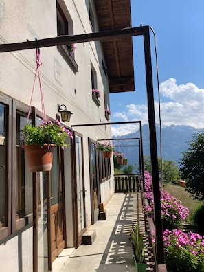 Un balcon agrémenté de jardinières suspendues, une balustrade en bois et une vue sur les montagnes.
