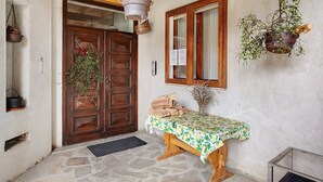 A rustic wooden door, a stone-paved entrance, a wooden bench with a table, and hanging plants. - Becca D'Aver Apartment with Mountain View, Shared Garden, and Wi-Fi (Semon)